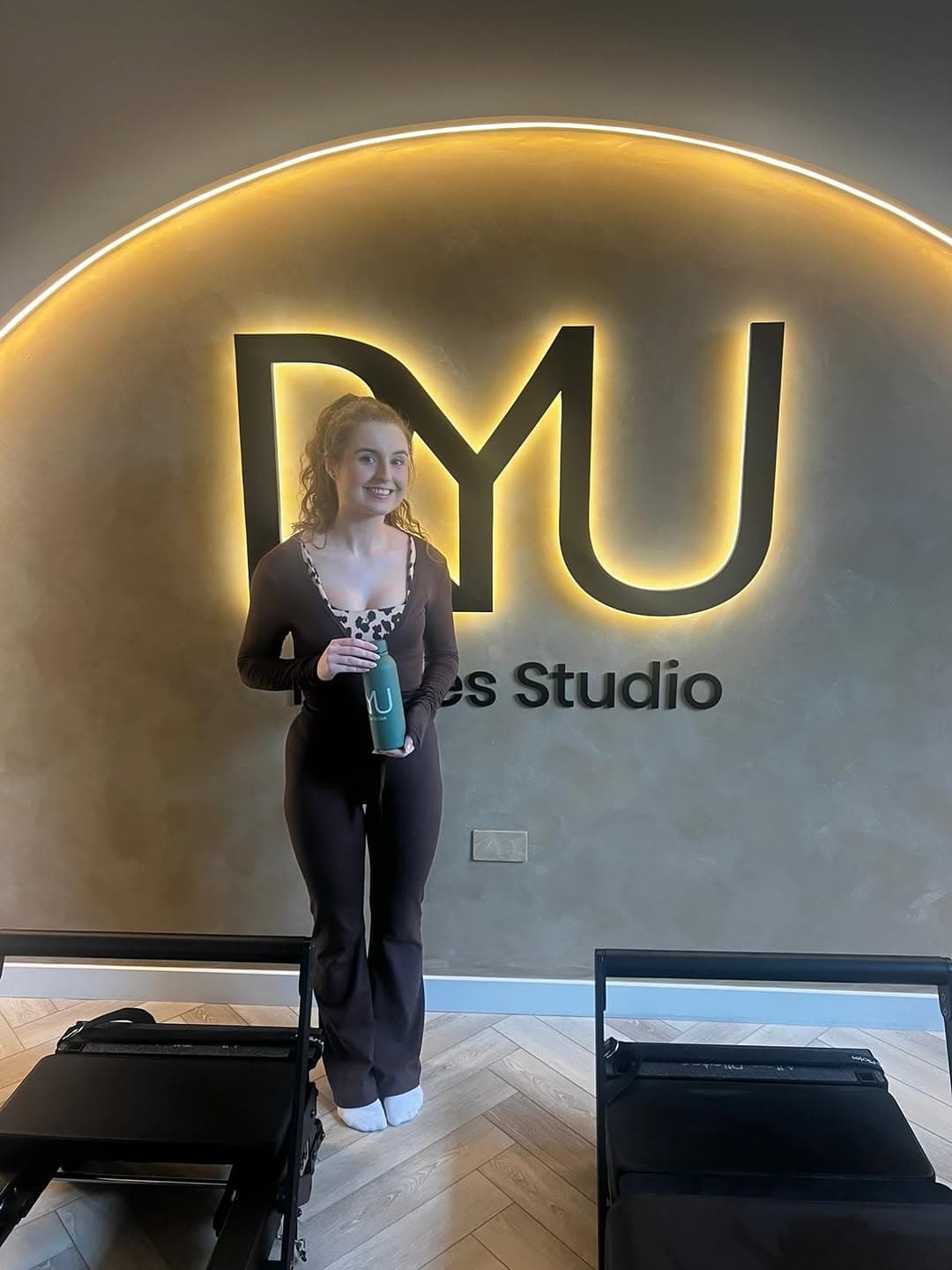Megan — RYU 50 Club member — standing in front of the RYU arch with a branded water bottle